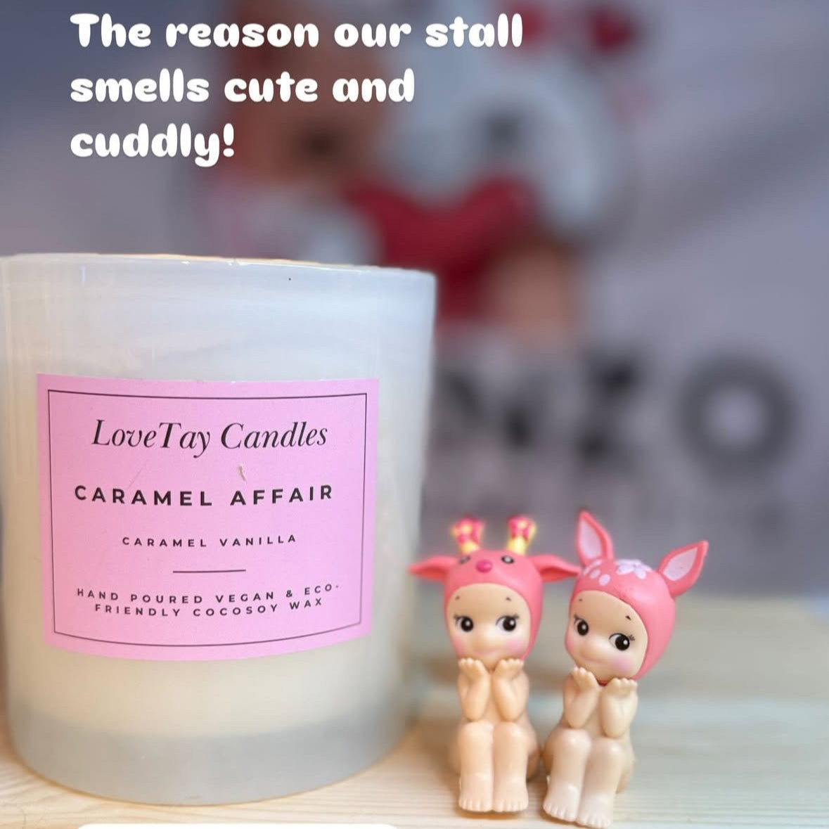 Candle labelled 'Caramel Affair' by Lovetay Candles with two small figurines on a blurred background.