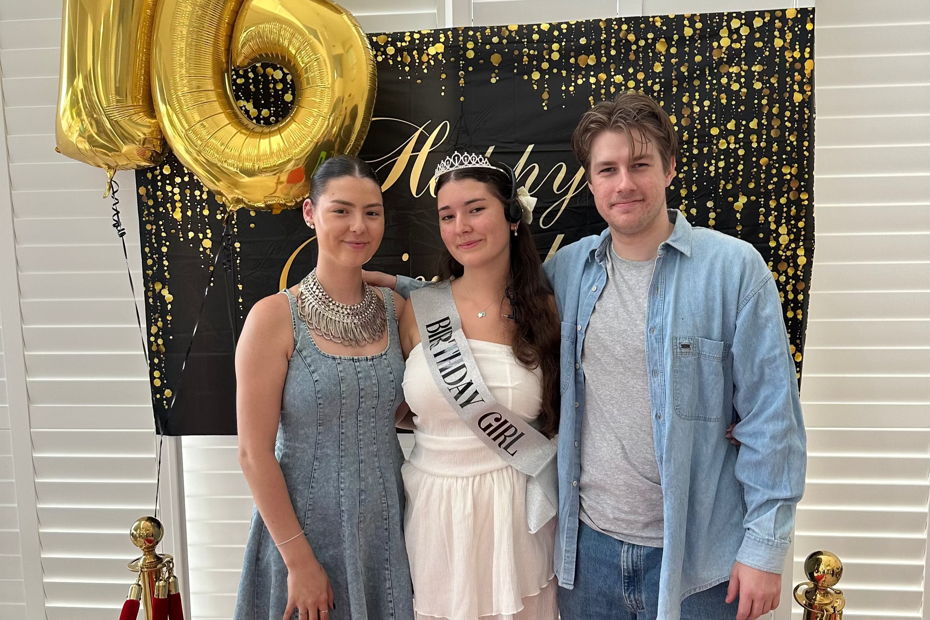 Three people posing in front of a '16' balloon and 'Birthday Girl' sign with a decorative backdrop. The LoveTay Candle Team