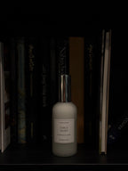 A frosted glass bottle of 'Early Night' body wash by 'LoveTay Candles' with a metallic silver cap, displayed on a dark bookshelf between books.