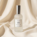 A frosted glass room spray bottle with a metallic silver cap, labeled 'EARLY NIGHT' by Luxe-Tay Candles, set against a draped beige fabric background.