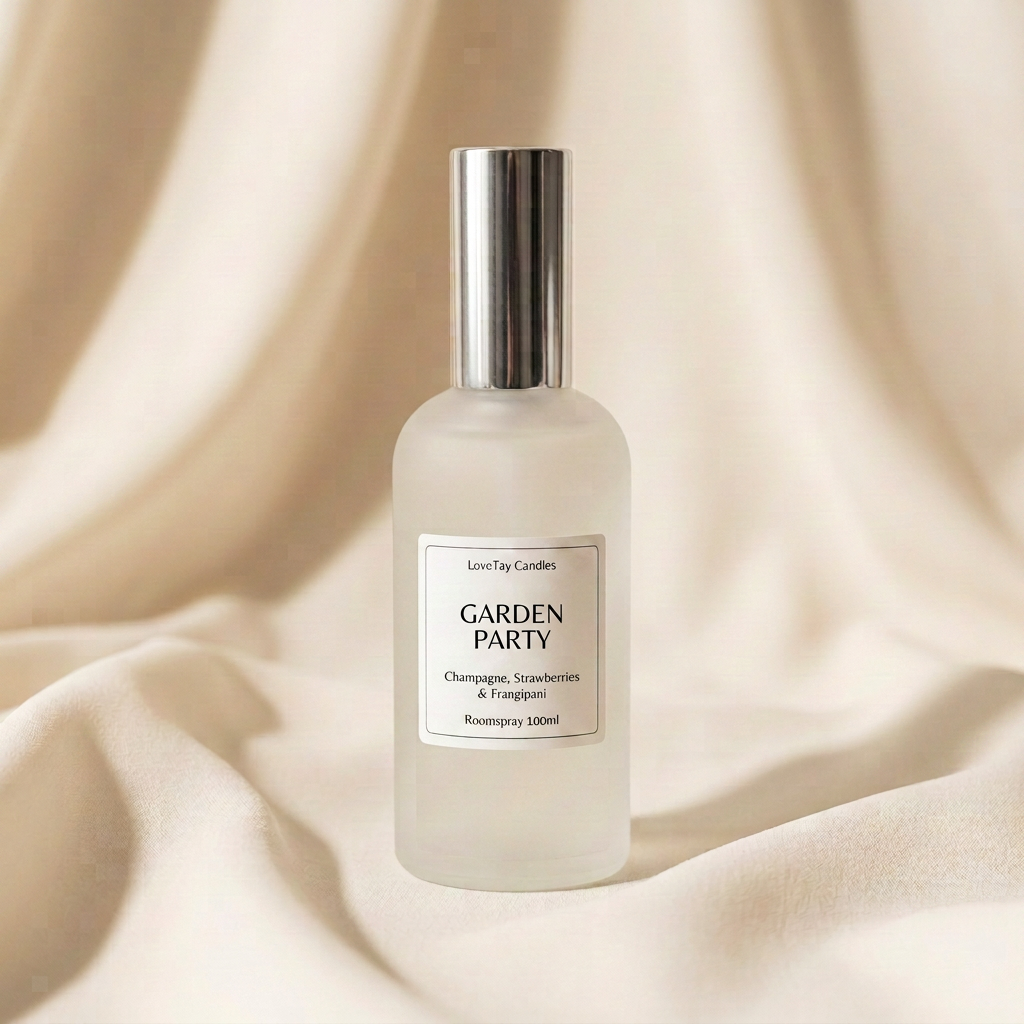 A frosted glass bottle of Love-Tay Candles 'Garden Party' rosemary spray, featuring a silver pump and a white label, set against a draped beige fabric background.
