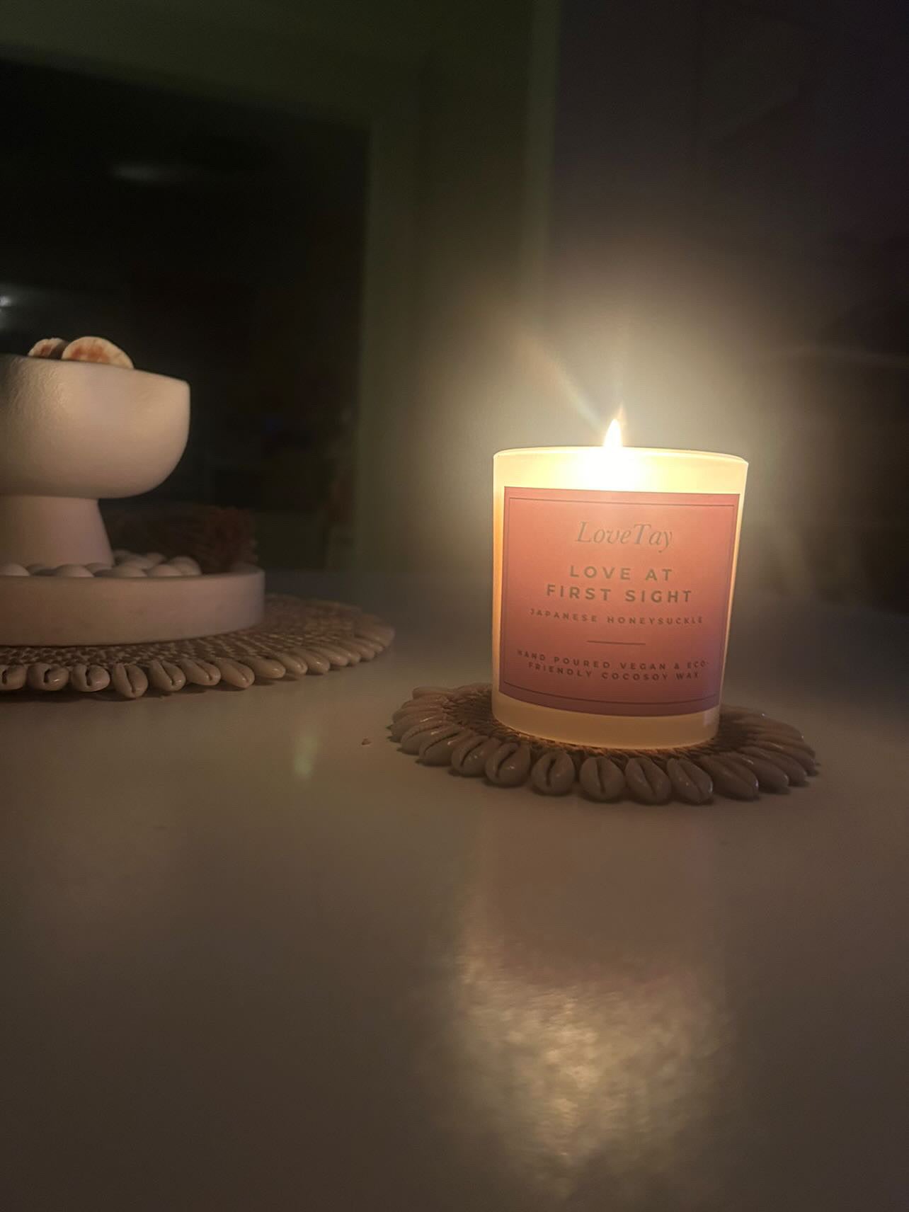 Candle labeled 'Love at First Sight' on a coaster with a blurred background