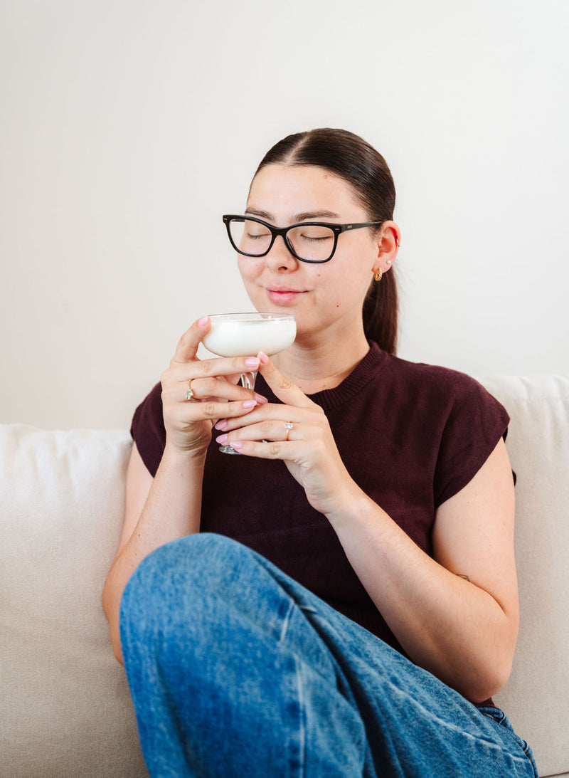 LoveTay Candles owner Taylah sitting on a couch holding a Mint Mojito cocktail candle. 